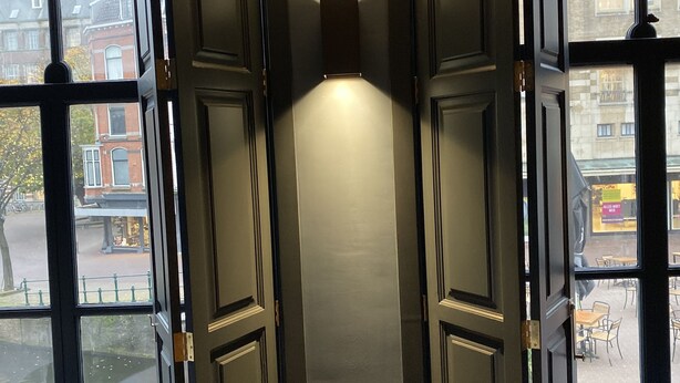 A narrow hallway with a door on the left and a window on the right. - CTY Books (Leiden)