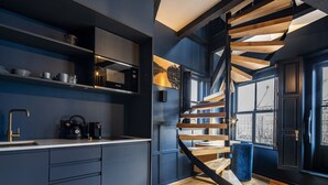 A modern kitchen with a built-in stove, a coffee machine, and a sink. There is a wooden staircase leading to an upper level. - CTY Books (Leiden)