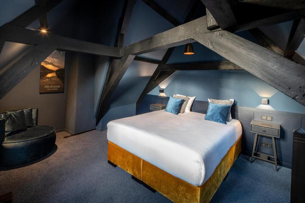 Quarto com uma cama grande, um sofá pequeno e uma mesa de cabeceira com abajur.