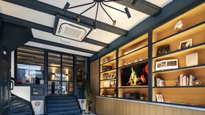 A hotel lobby with a staircase, wooden shelving with books and decorative items, and a fire feature. - CTY Books (Leiden)