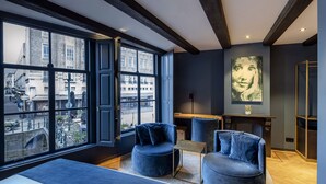 A modern room with large windows, a bed, two blue armchairs, and a small table. - CTY Books (Leiden)