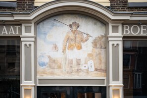 Un murale raffigura un uomo che tiene un fucile sulla facciata di un edificio.