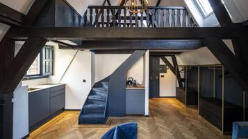 Un loft amplio con escalera de madera, una zona de cocina y una entreplanta con balcón.