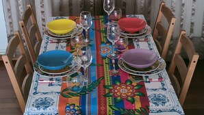A dining table set with colorful tablecloths and plates, surrounded by wooden chairs. - Apartamento San Antonio (Monforte de Lemos)