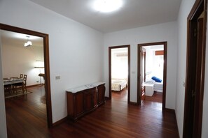 Une pièce spacieuse avec un plancher en bois, une grande armoire et un lit à l’arrière-plan.