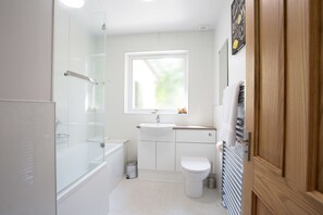 A modern bathroom with a glass shower enclosure, a white sink, and a toilet. - Juniper Hill, Loch Achilty (Strathpeffer)