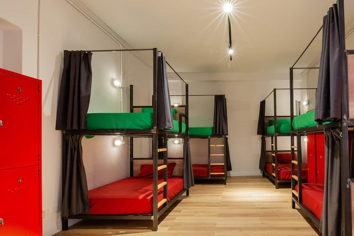 Une chambre de dortoir avec des lits superposés, une armoire rouge et un plancher en bois.