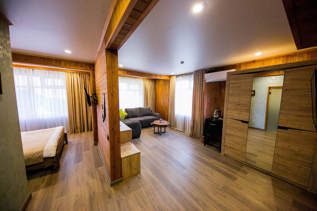 A room with a bed, sofa, small table, and a built-in wardrobe.