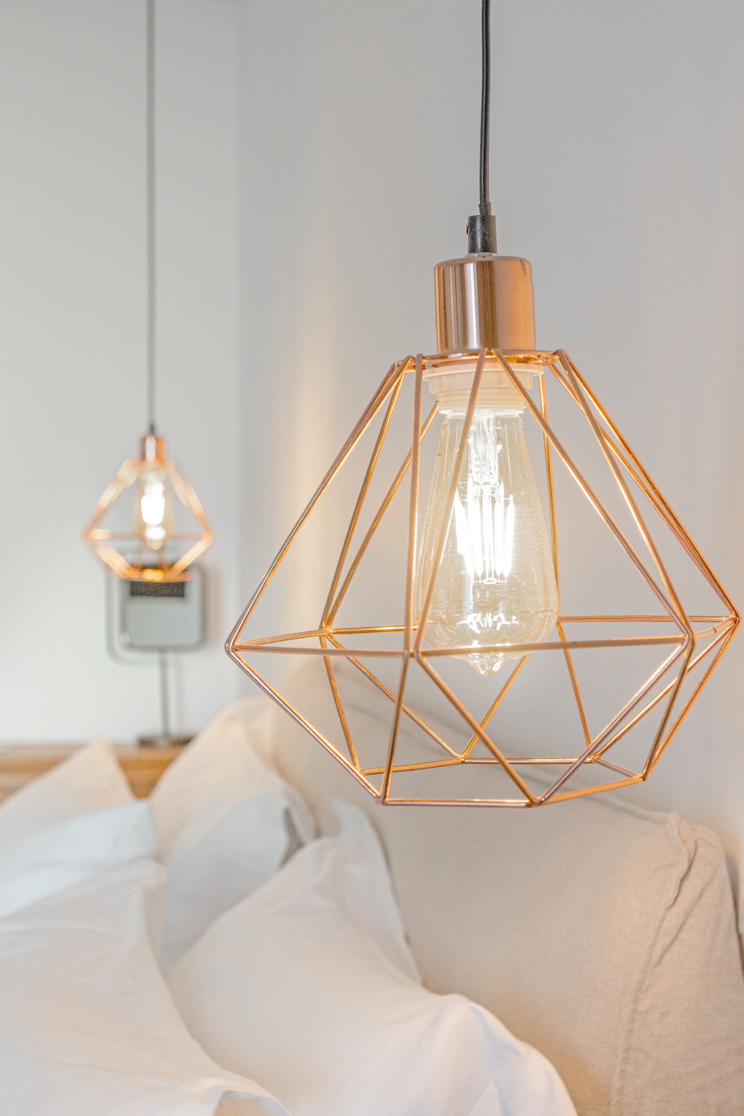 Un dormitorio moderno con una lámpara colgante de diseño geométrico y una mesita de noche sencilla.