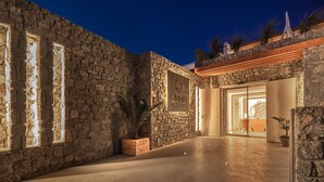 A stone-walled building with a wooden door and a sign reading "OMNIA MYKONOS". - Omnia Mykonos Boutique Hotel & Suites (Mykonos)