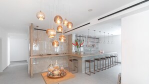 A modern kitchen with a central island, pendant lighting, and a bar area with stools. - Omnia Mykonos Boutique Hotel & Suites (Mykonos)