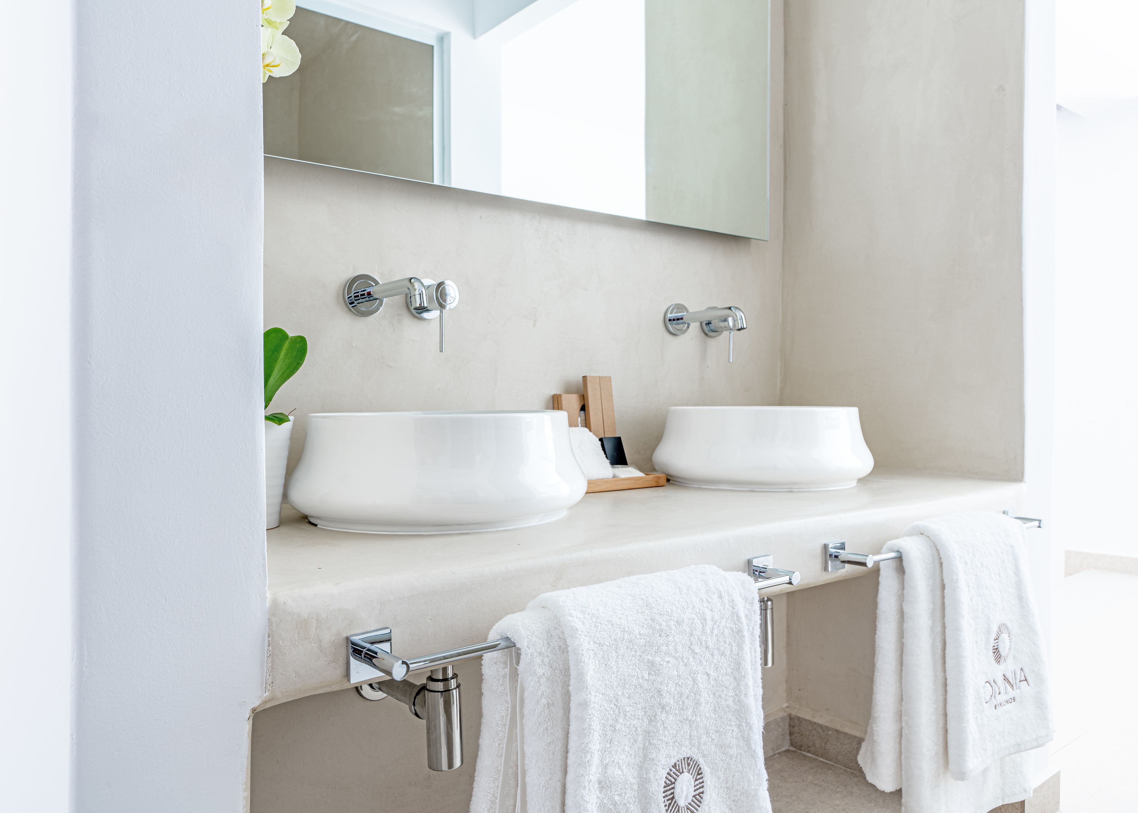 Une salle de bain moderne avec deux lavabos, un grand miroir et des serviettes suspendues à un porte-serviettes.
