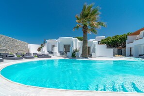 A modern pool area with white buildings, palm trees, and outdoor seating. - Omnia Mykonos Boutique Hotel & Suites (Mykonos)