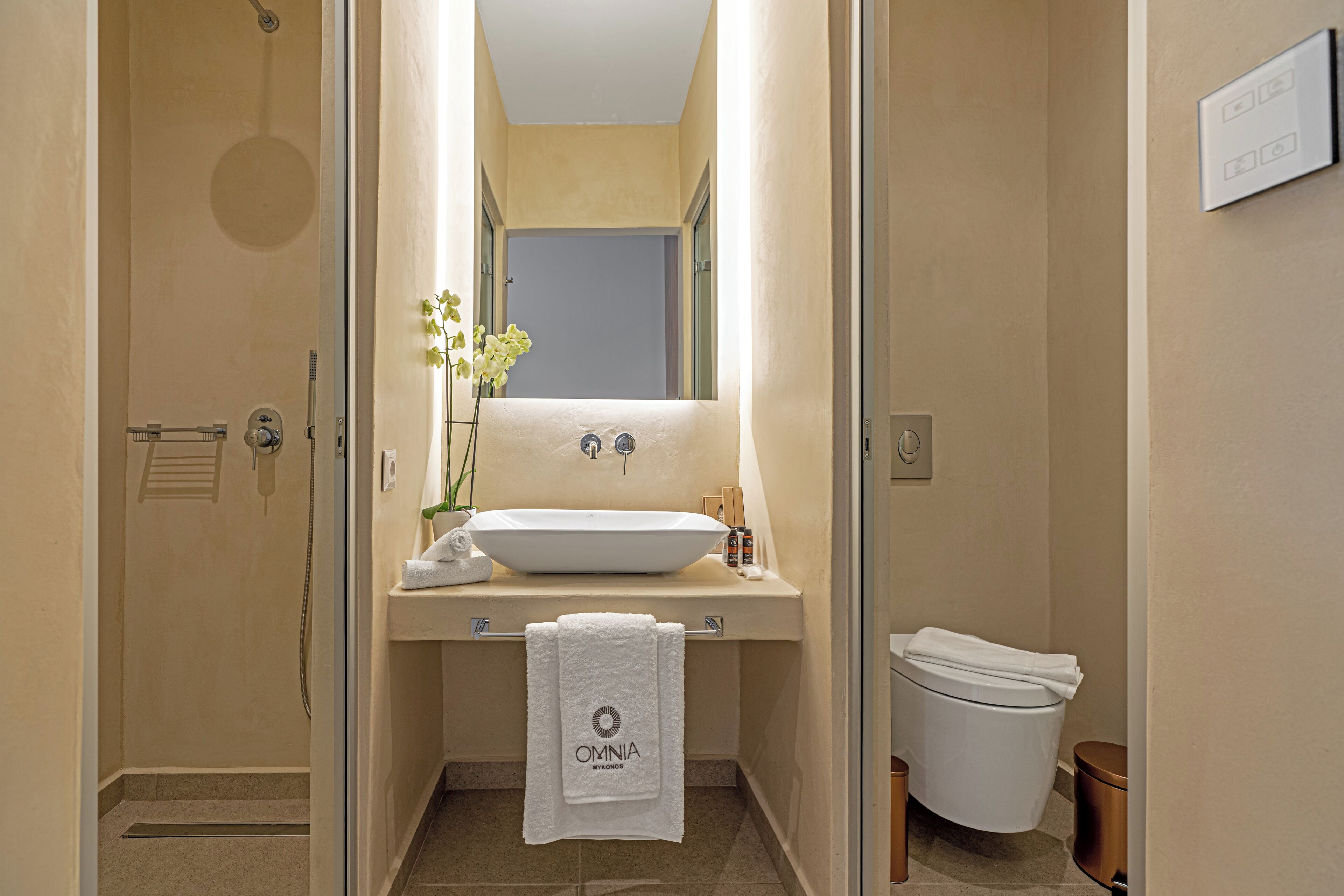 A bathroom with a white sink, a towel rack, a toilet, and a shower area.