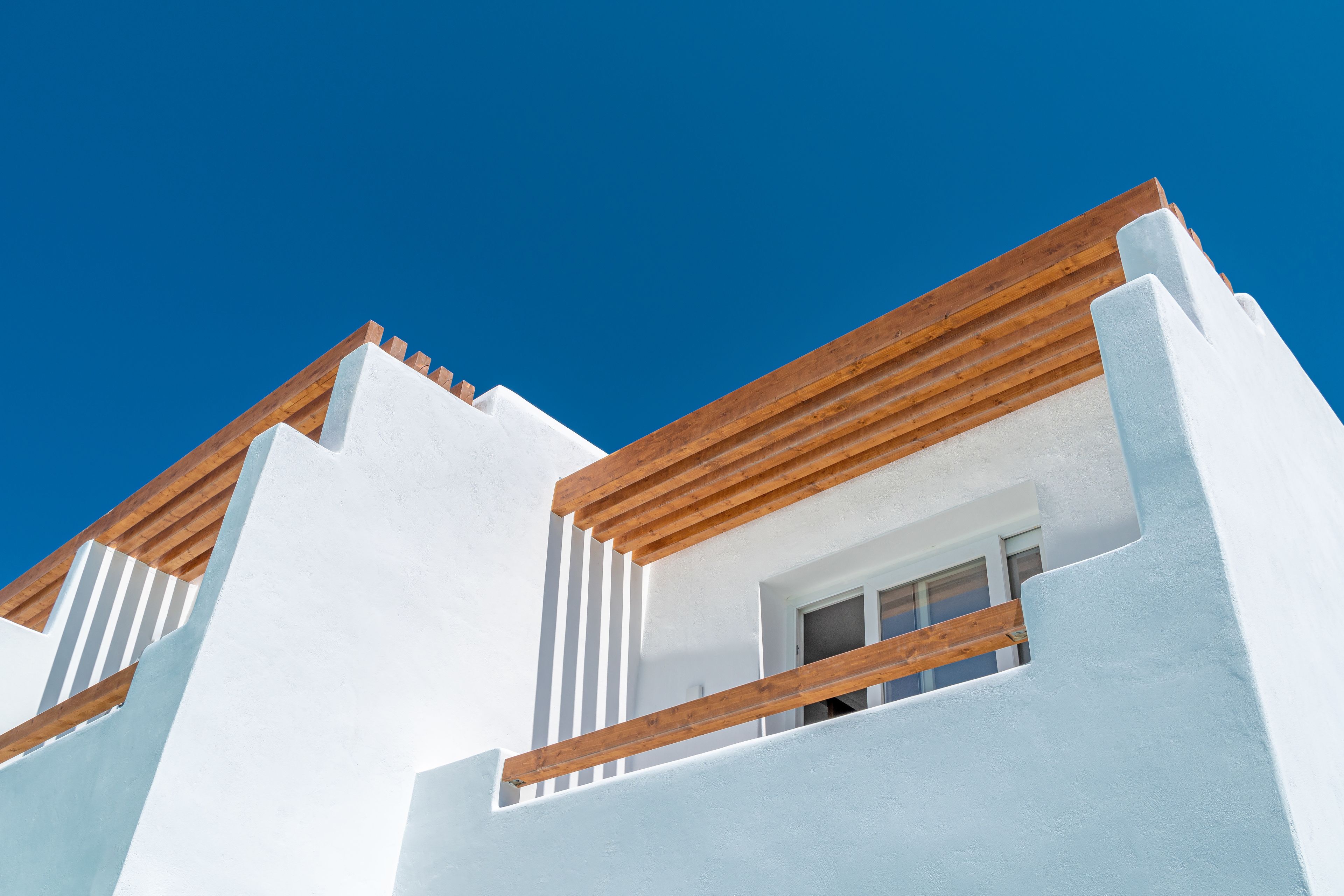 A modern building with white walls and wooden beams on the roof.