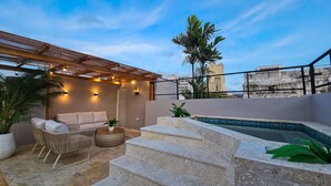 A rooftop terrace with a seating area, a small pool, and a pergola with string lights.