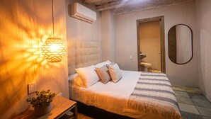 A bedroom with a bed, bedside lamp, and a potted plant.