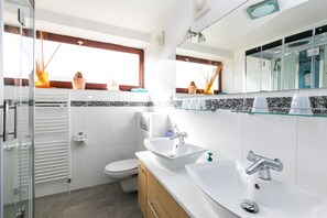 Une salle de bain moderne avec une douche à parois de verre, un lavabo blanc et des toilettes.