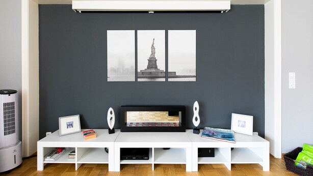 Ein modernes Wohnzimmer mit einer weißen Unterhaltungsanlage, einem gerahmten Bild einer Statue und einem Kamin.