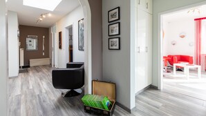 Eine moderne Hotelhalle mit einer Rezeption, einem schwarzen Bürostuhl, einem an der Wand befestigten Bilderrahmen und einer roten Couch im Hintergrund.