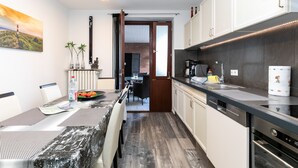 Eine moderne Küche mit Essbereich, ausgestattet mit einer schwarzen Arbeitsplatte, weißen Schränken und Blick in den Essraum.