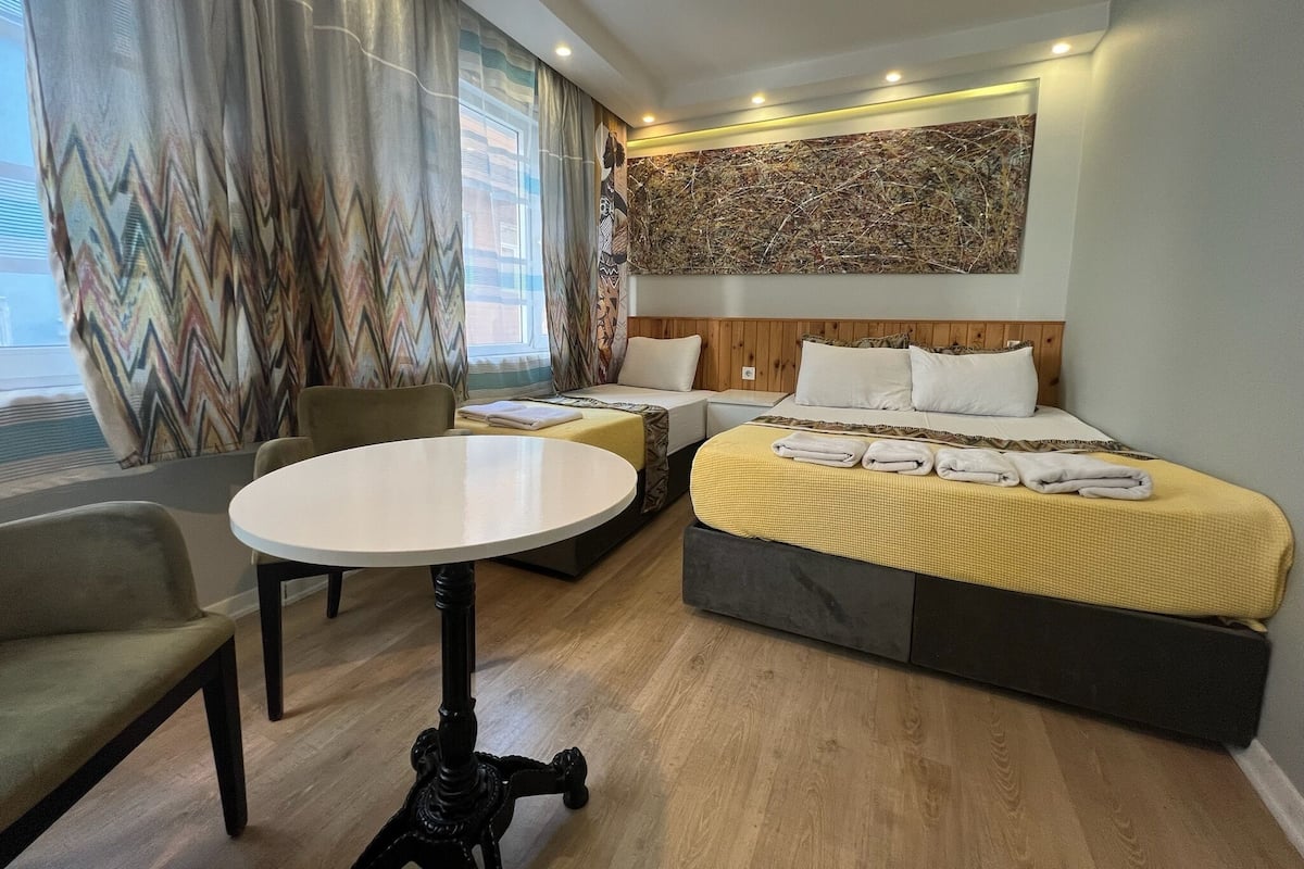 A hotel room with a bed, two bedside tables, a round table, and a chair.