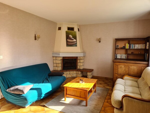 A living room with a stone fireplace, a blue sofa, a wooden coffee table, and a bookshelf.
