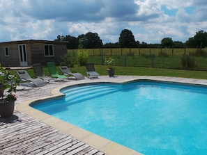 Une piscine avec une terrasse en bois et des chaises longues.