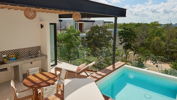 A modern outdoor pool area with lounge chairs and a dining table, surrounded by greenery and a clear sky. - Romantic Penthouse Studio Get Away With Private Splash Pool- PENT HOUSE 3 B- By Salt-Kisses (Tulum)