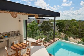 Ein moderner Poolbereich im Freien mit Liegestühlen und einem Esstisch, umgeben von viel Grün und blauem Himmel.