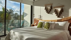 A modern bedroom with a large bed, a wooden headboard, and a view of greenery outside. - Romantic Penthouse Studio Get Away With Private Splash Pool- PENT HOUSE 3 B- By Salt-Kisses (Tulum)