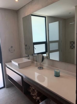 A modern bathroom with a large mirror, two sinks, and a small candle on the vanity.