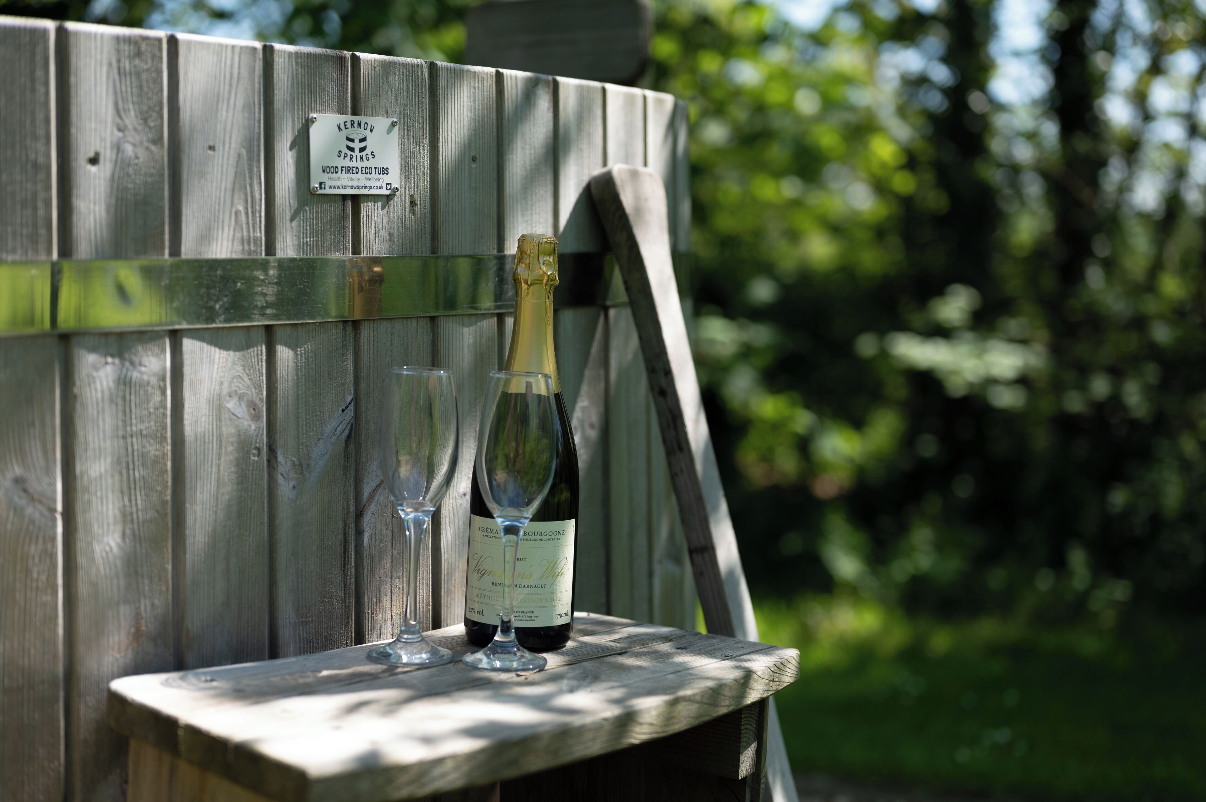 A wooden wine barrel with a label and two wine glasses on a wooden table.