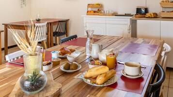 A breakfast table with bread, pastries, a pitcher, and a cup.