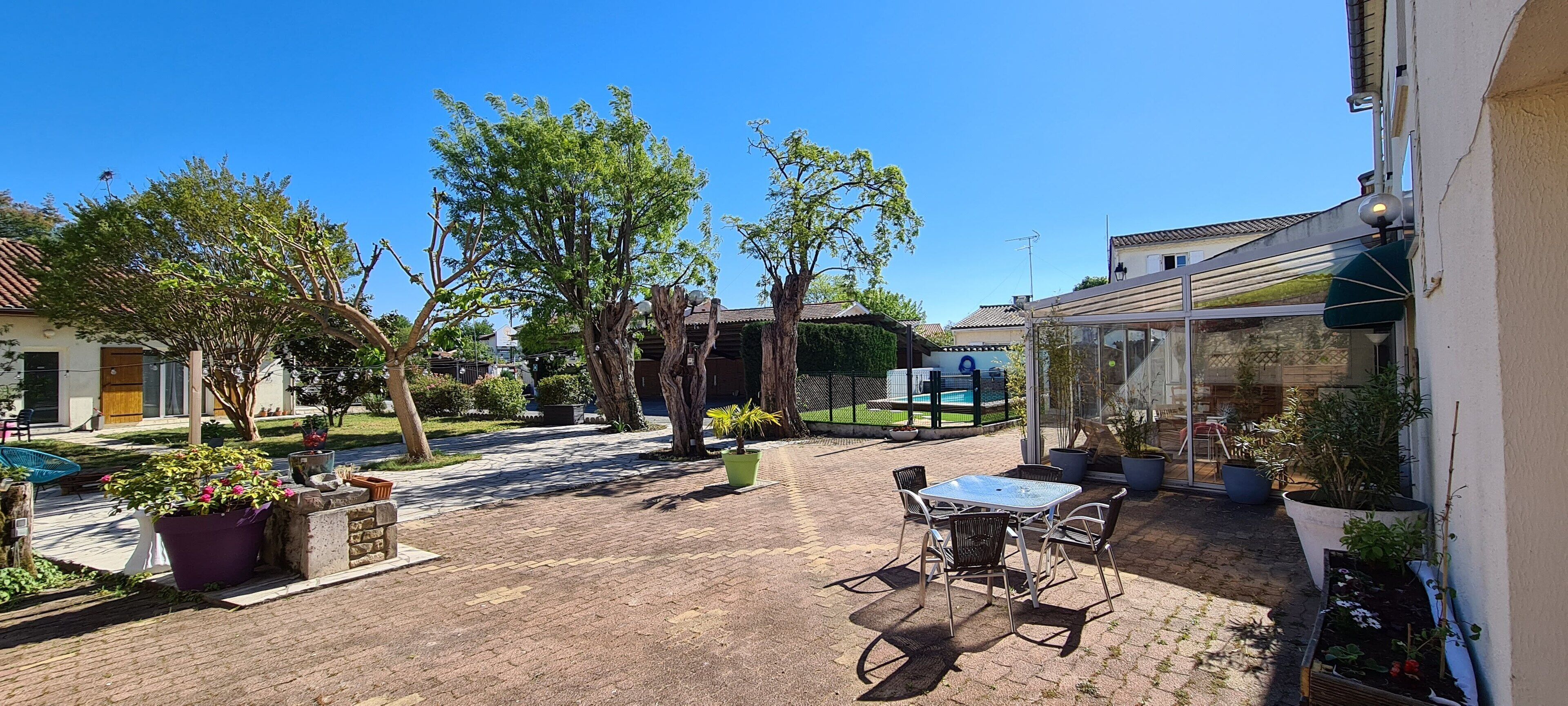 A courtyard with a patio area, potted plants, and a glass-enclosed space.