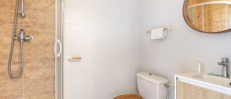 A bathroom with a toilet, shower, and sink.