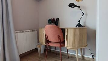 A room with a wooden desk, a red chair, a black lamp, and decorative sunburst mirrors on the wall.