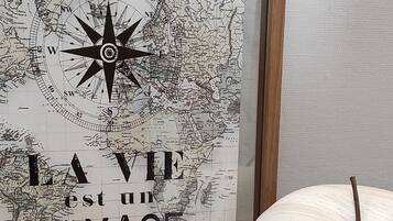 A framed map with a compass rose and the phrase "LA VIE est un VOYAGE" in the center, placed on a wooden floor next to a white, textured object.