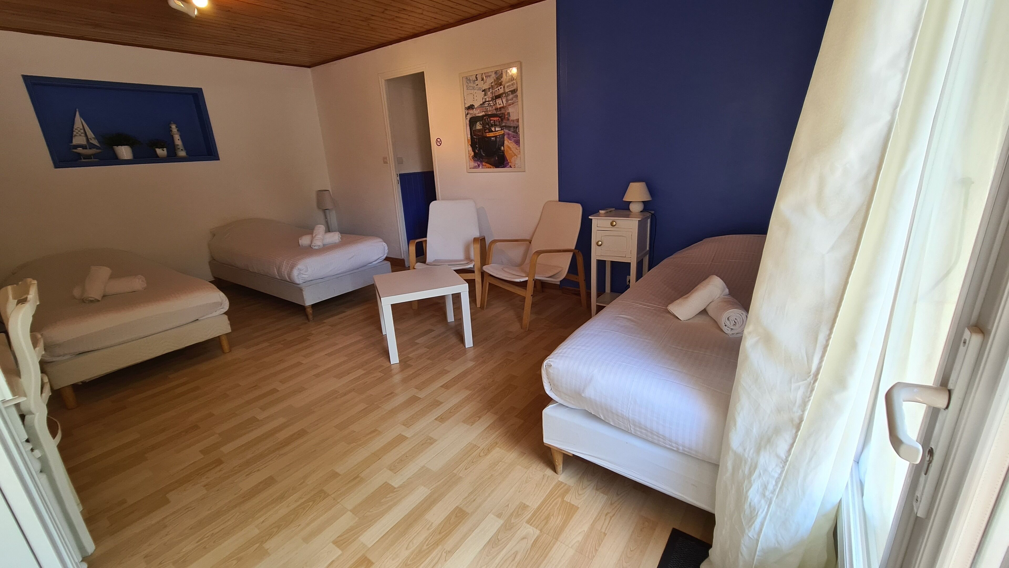 Una habitación con dos camas, una silla, una mesita y una lámpara.