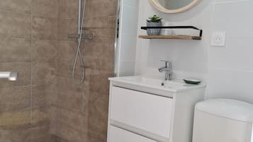 Un baño con ducha, inodoro, lavamanos y espejo.