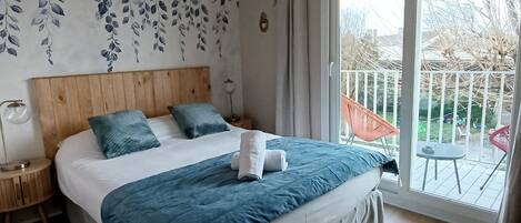 A bedroom with a wooden bed, a blue bedspread, and a view of the outdoors through a sliding glass door.