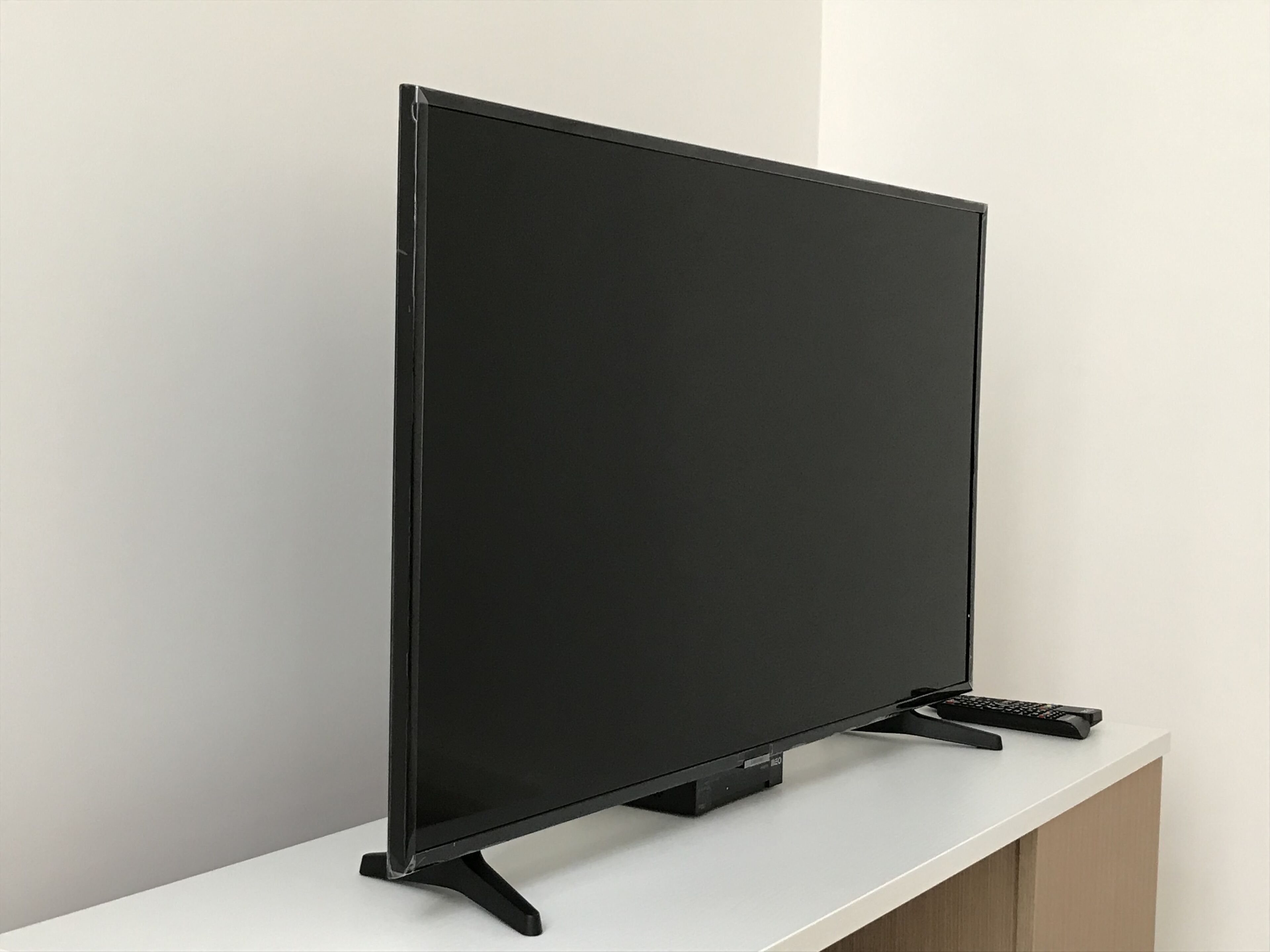 A flat-screen TV on a white stand against a plain wall.