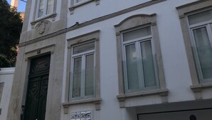 Un edificio de varios pisos con fachada simétrica, ventanas grandes y puerta verde.
