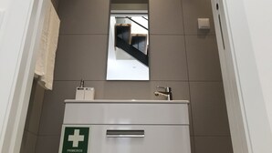 Un pasillo con un cartel de primeros auxilios, un espejo y una escalera.