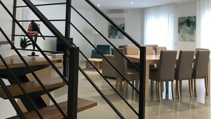 Un interior moderno con una escalera, comedor y obras de arte.