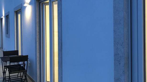 Fachada moderna de un edificio con amplias ventanas y mesas al aire libre.