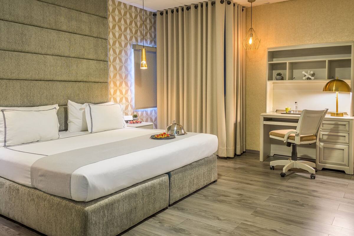 A hotel room with a large bed, a desk, and a chair.