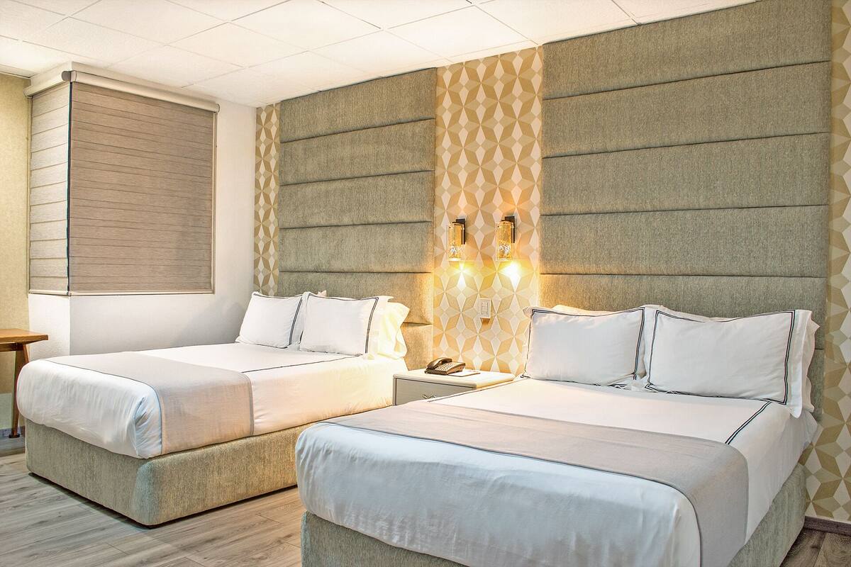 A hotel room with two beds, a wooden headboard, and a geometric-patterned accent wall.