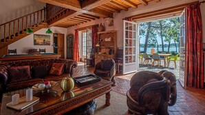 A spacious living room with a wooden staircase, leather furniture, and a view of the outdoors.