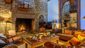 A cozy living room with a stone fireplace, leather sofa, and a television.